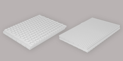 Två vita dräneringsskivor, en med cirkulära former och en med räfflor, på en neutral bakgrund.